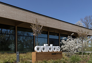 Homeground adidas Herzogenaurach Foto von einem Gebäude mit Flachdach. Zuvor ist ein Schild mit der Aufschrift adidas