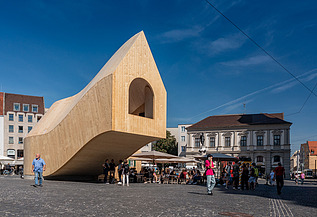 NEXT500 Pavillon, Augsburg Foto des NEXT500-Pavillons auf dem Augsburger Marktplatz. Sie können ein modernes Holzgebäude sehen.