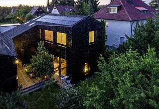 Wohnhaus Stuttgart Foto eines Wohnhauses aus Holz und mit dunkler Holzfassade. Abendstimmung.