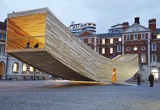 The Smile - Skulptur Design Festival London Foto von der geschwungenen Holzskulptur The Smile in London. Der Holzkasten ist begehbar und soll einen lachenden Mund darstellen.