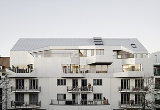 Aufstockung Rottmannstraße München Foto eines mehrgeschossigen Gebäudes mit weißer Fassade. Aufstockung mit LENO-Brettsperrholz.